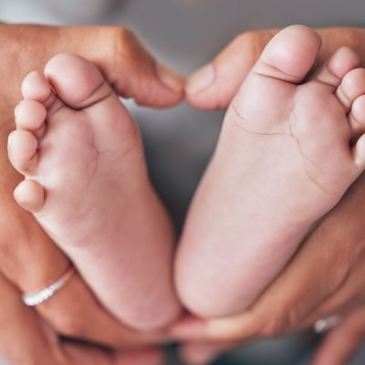 Baby, feet and hands of mother closeup with newborn for love, care or family bond in their home. Zo.
